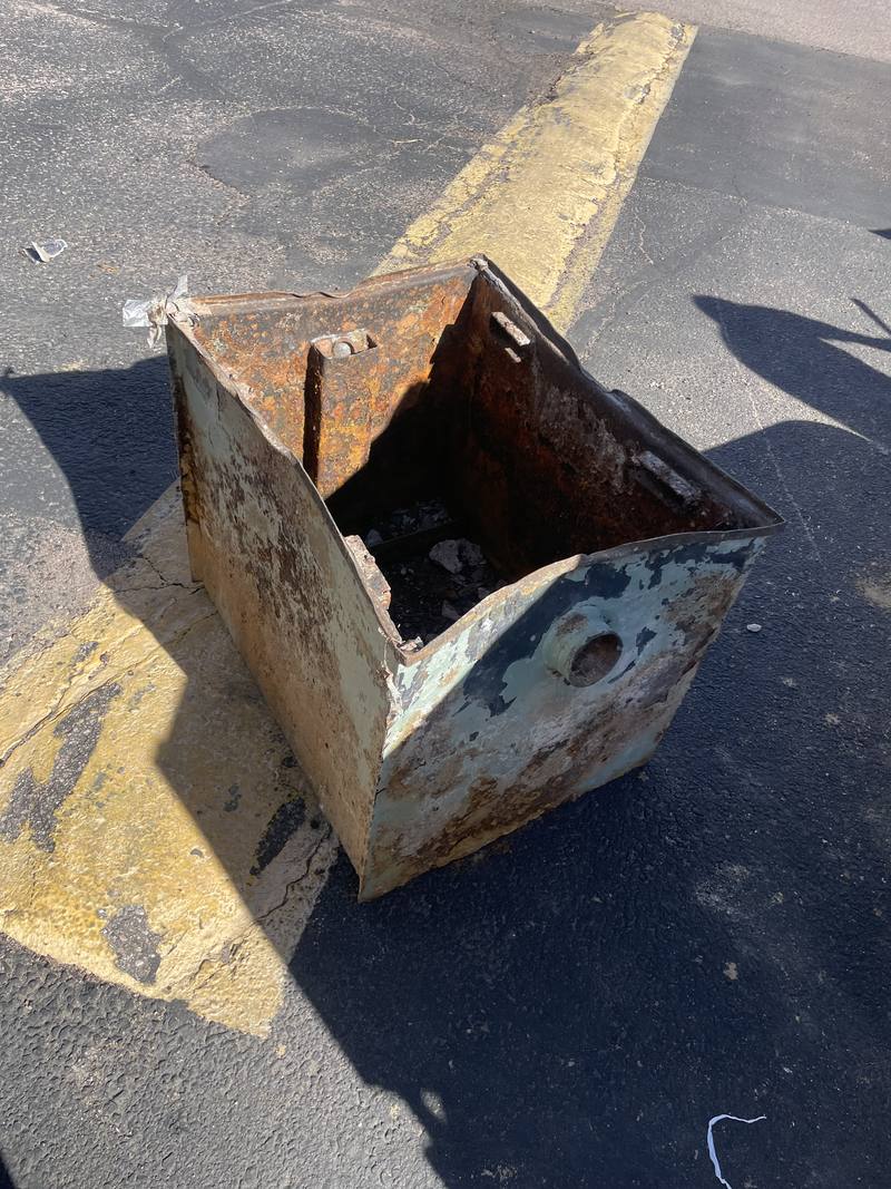 Old rusted steel grease trap pulled out and sitting in a parking lot