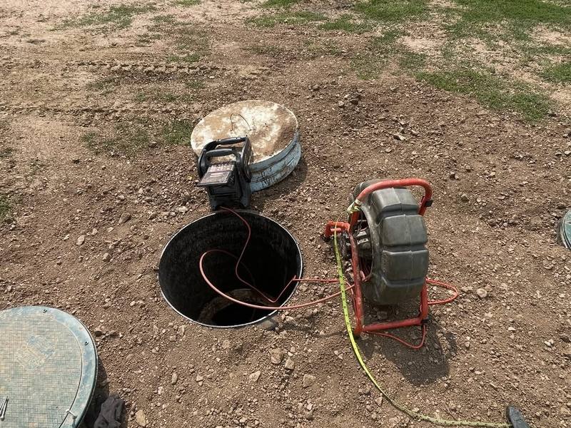 Sewer inspection camera reel set up beside an open septic tank access